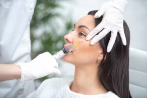 Cosmetologist marking woman's face before dermal filler injection treatment