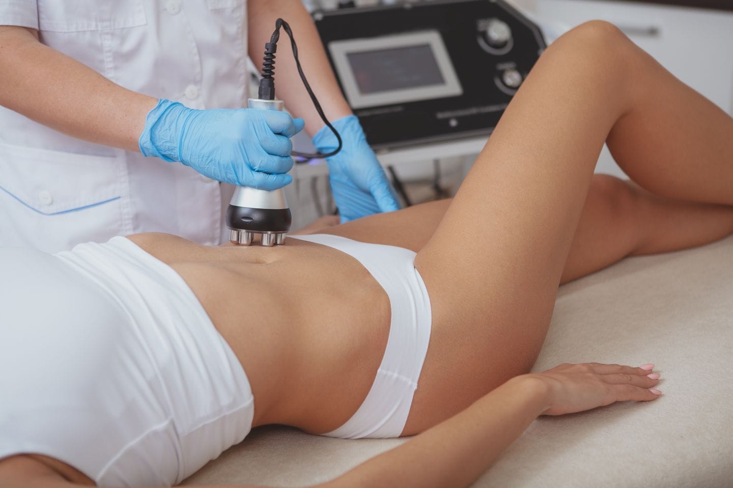 Practitioner performing a radiofrequency body contouring treatment on a woman’s abdomen at a clinic