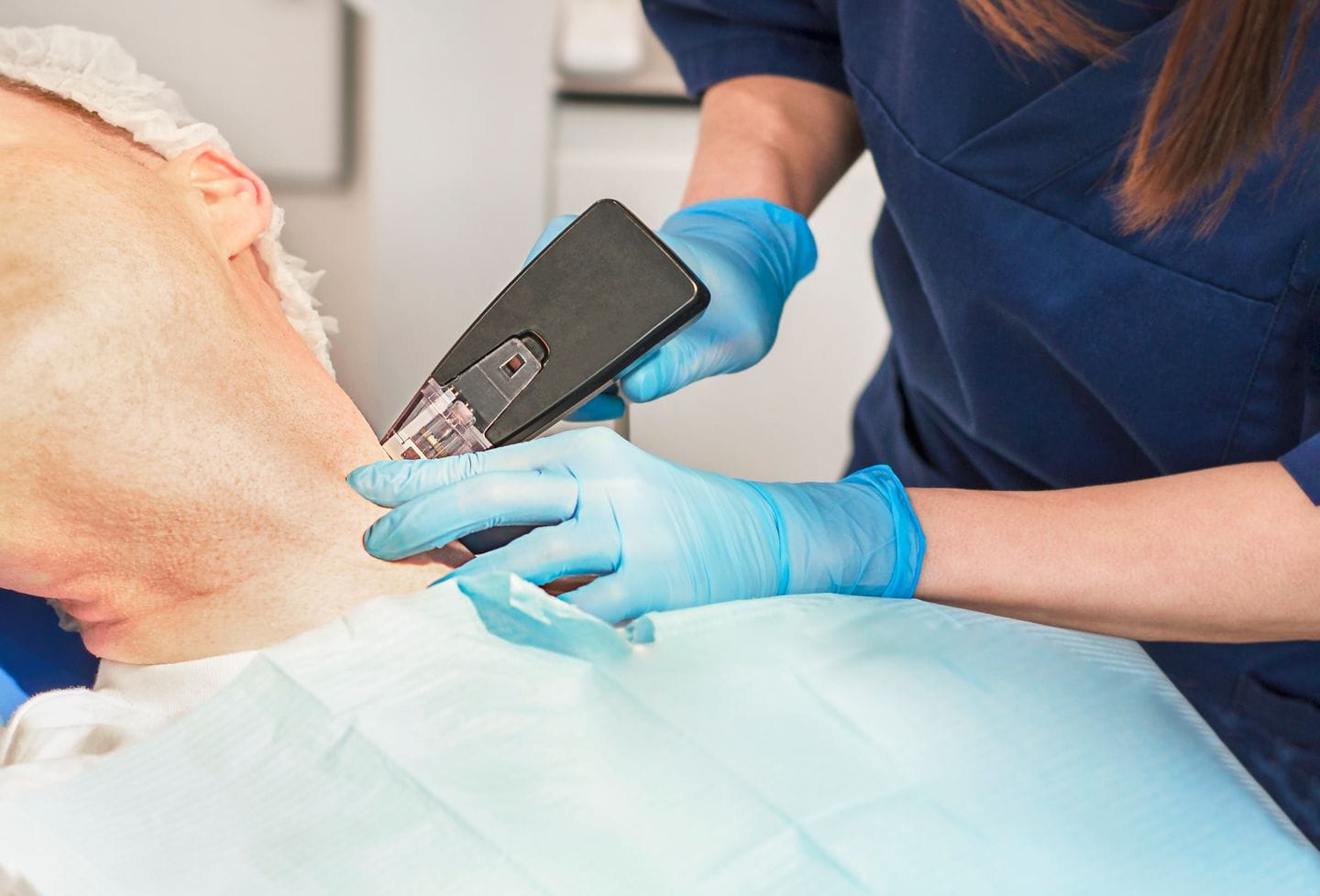 esthetician applying skin tightening device to womans neck during morpheus8 ultherapy treatment