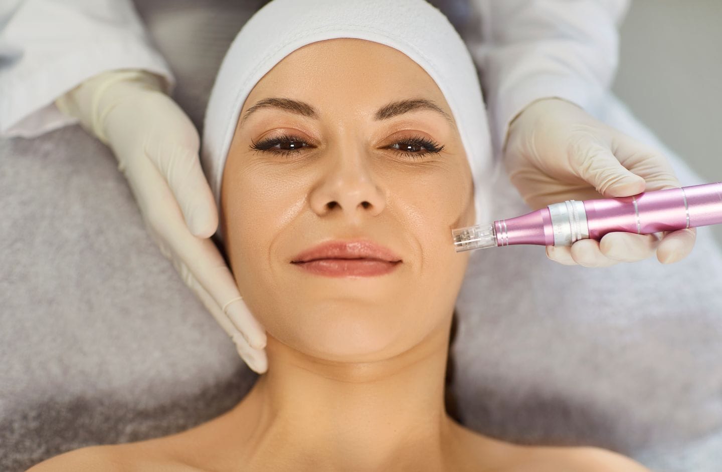 Esthetician performing a microneedling treatment on a relaxed woman’s face at a medical spa